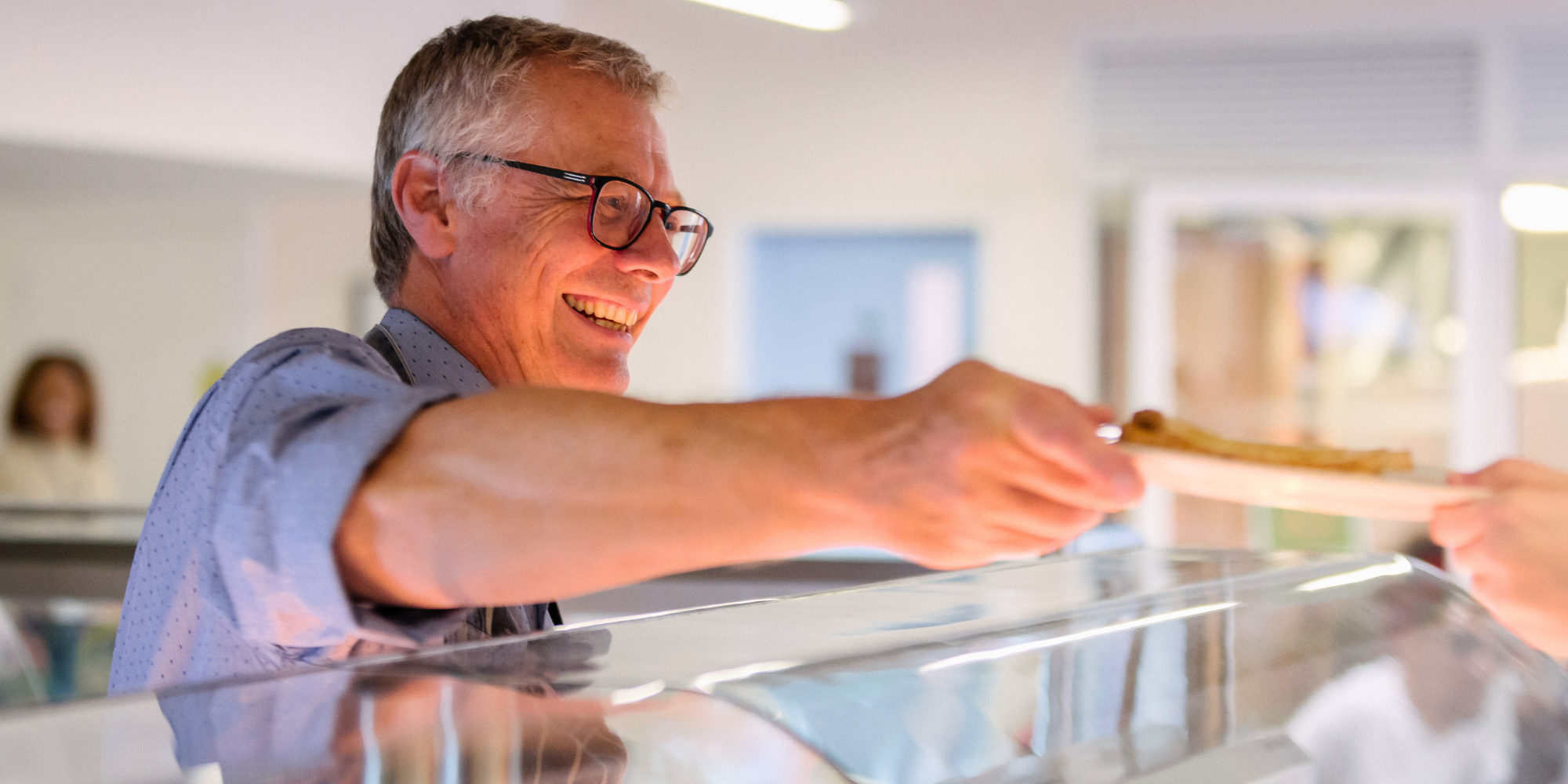 man smiling and handing out a plate of food