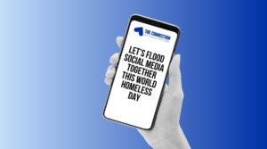 Set against a blue background, a hand holds a mobile phone where the display reads "Let’s flood social media together this World Homeless Day" to promote a planned social media takeover